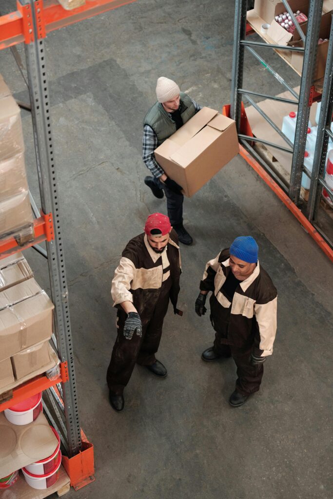Team of workers managing inventory in a warehouse, emphasizing logistics and teamwork.